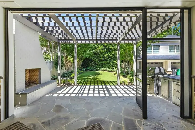 A flagstone patio with a pergola and an outdoor fireplace.