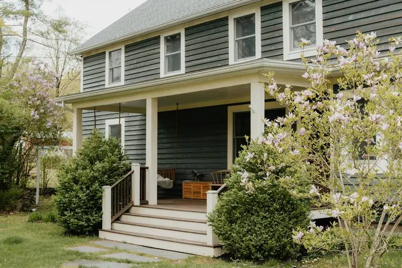 A grey house with wooden porch steps and a railing.