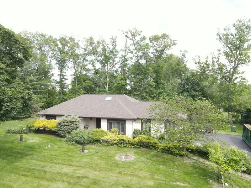 A suburban house among trees with a brown shingle roof.
